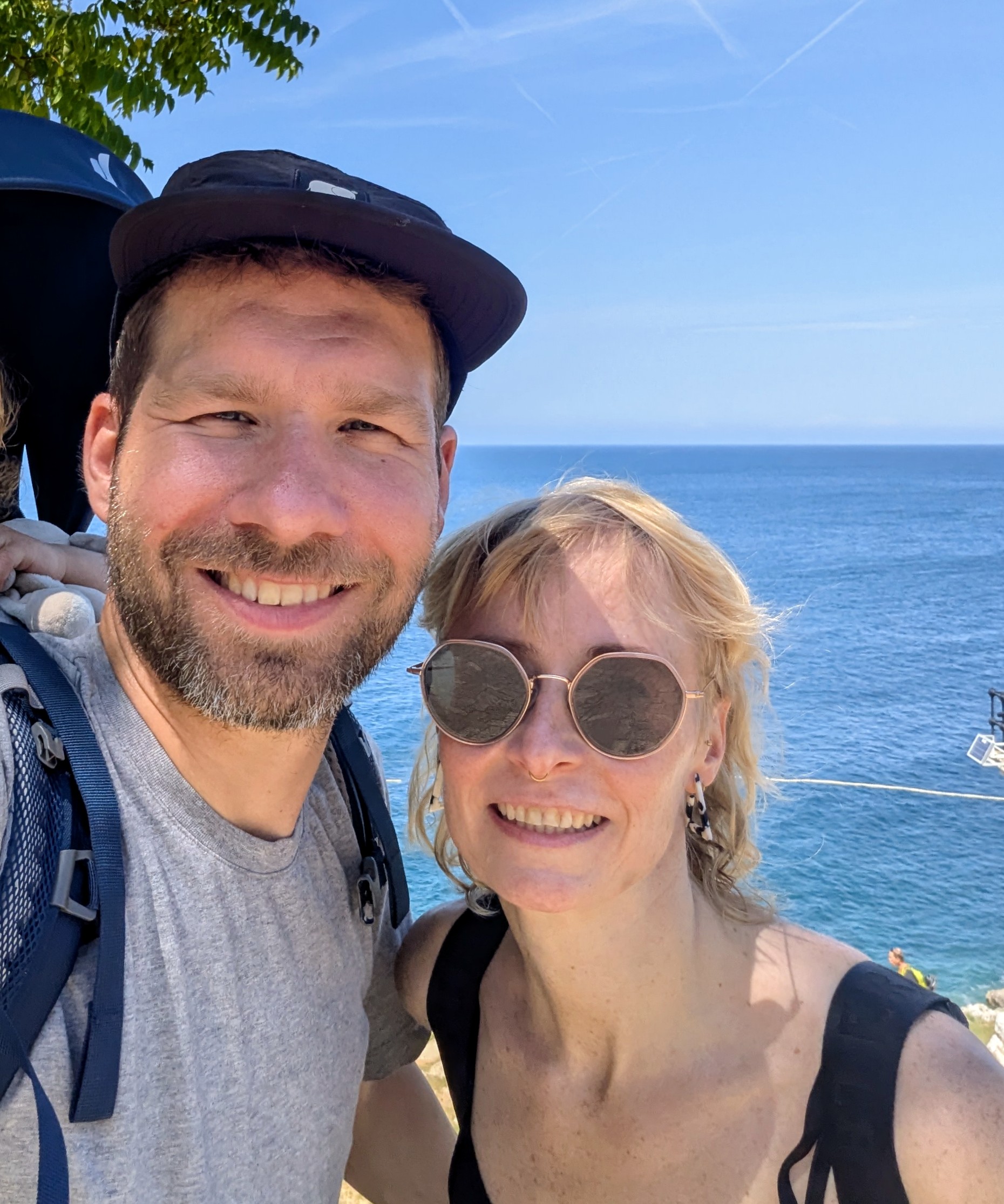 Alex and Pia, the founders of Ricky, on a coastal hike with their child in a carrier.